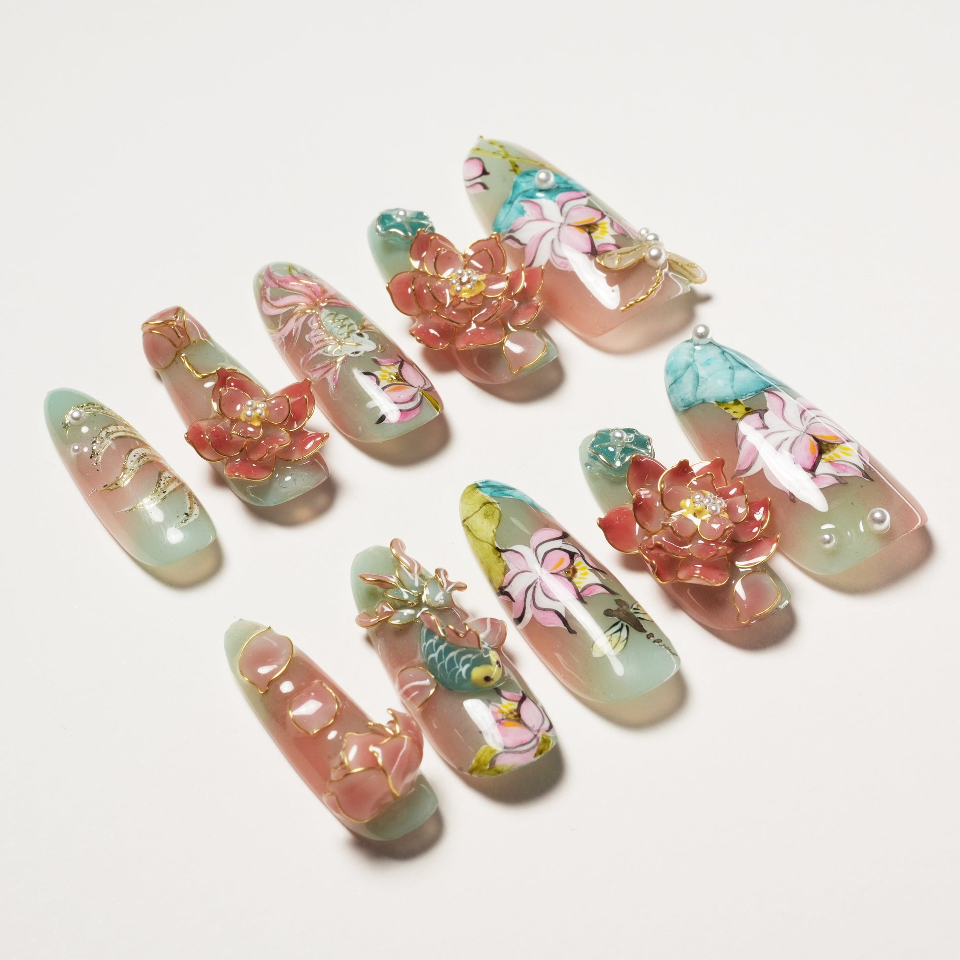 Set of decorative artificial nails with floral, fish, and 3D rose designs on pastel pink and teal bases