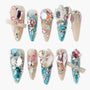 Set of ten long acrylic nails decorated with colorful crystals, gems, pearls, and glitter in pink, blue, and nude tones