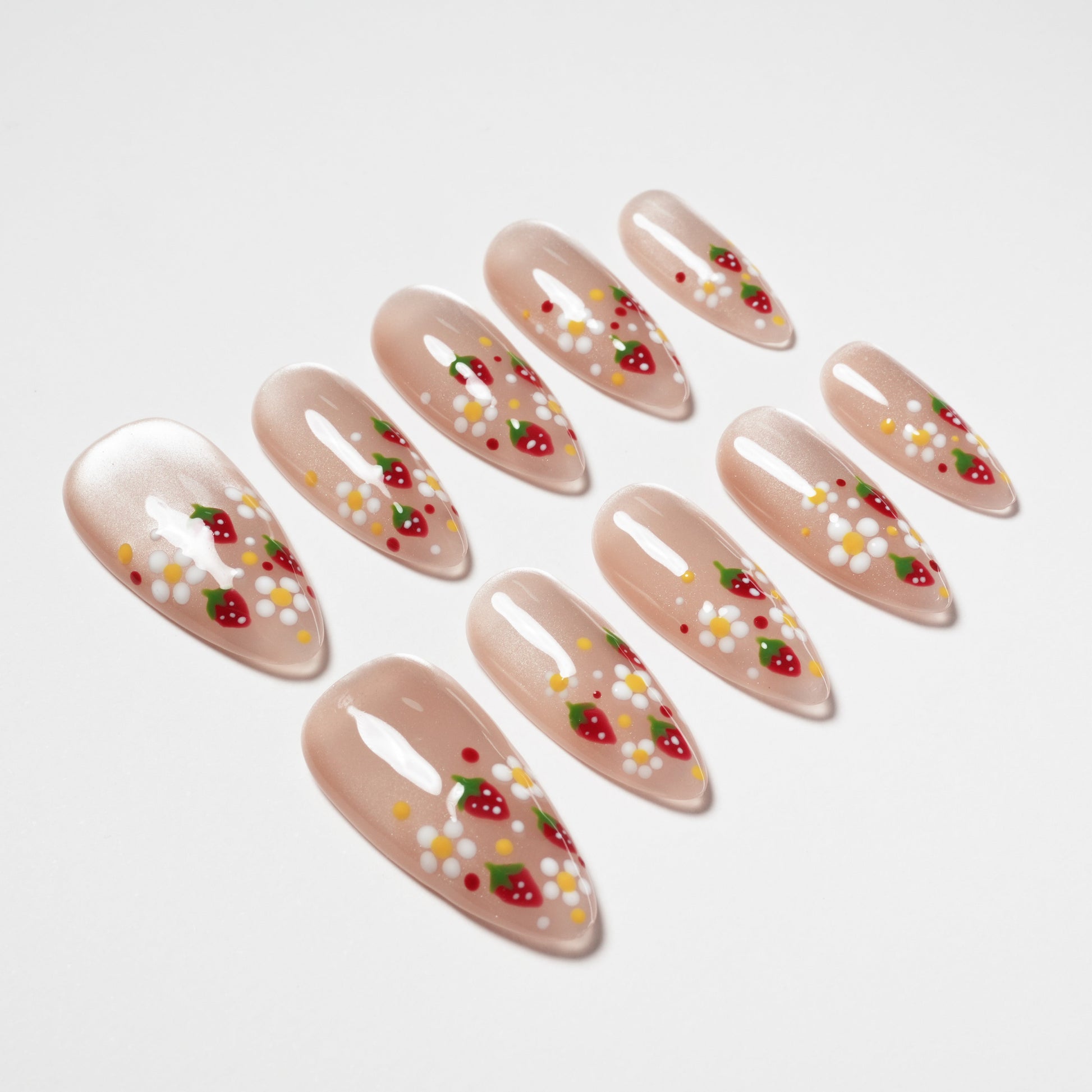 Almond-shaped press-on nails with strawberry and daisy floral nail art on nude base