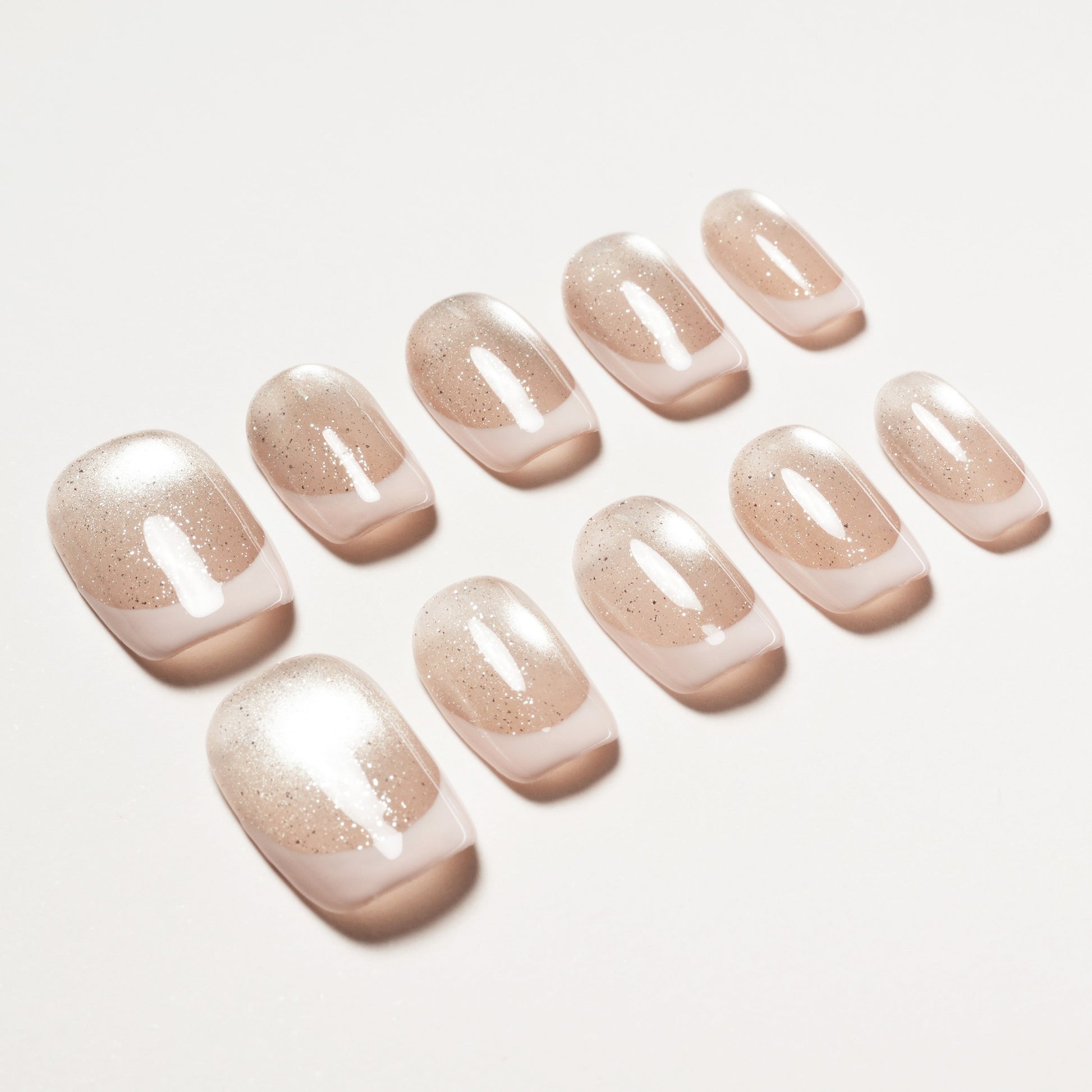 Set of nude glitter press-on nails arranged on a white background, glossy finish