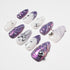 Set of purple and white artificial nails with metallic and pearl embellishments on white background