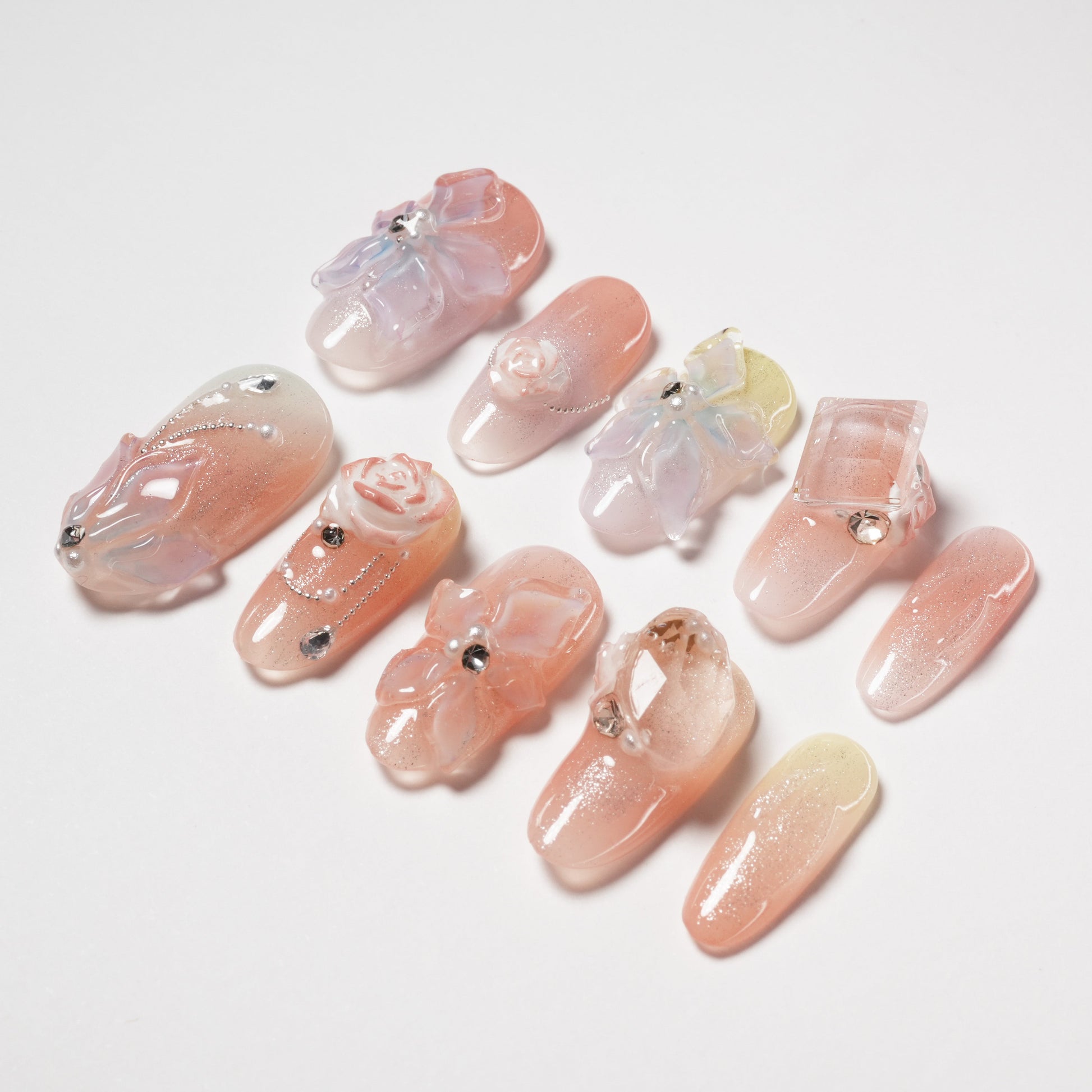Handmade press-on nails with 3D floral and gem designs in pastel and pink hues
