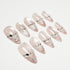Set of pale pink press-on nails with silver rhinestone and gem embellishments on white background