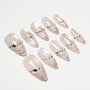 Set of pale pink press-on nails with silver rhinestone and gem embellishments on white background