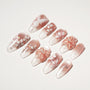 Handmade press-on nails with pink gradient, white floral designs, 3D flowers, and glitter accents