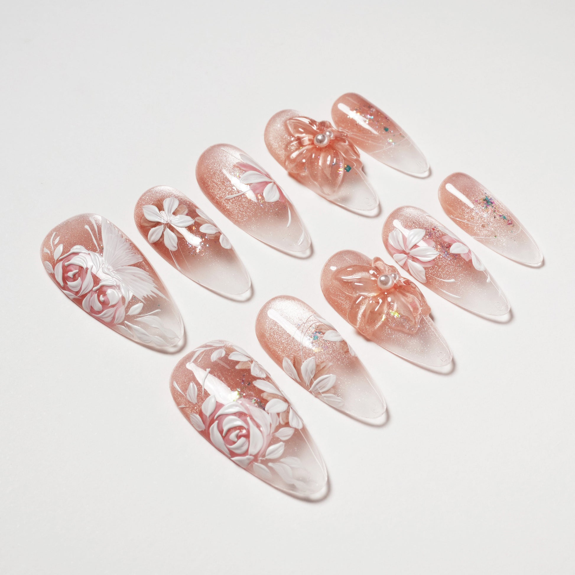 Handmade press-on nails with pink glitter, 3D floral designs, and white rose accents
