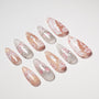 Handmade press-on nails with pink, white, and glitter floral designs on a white background