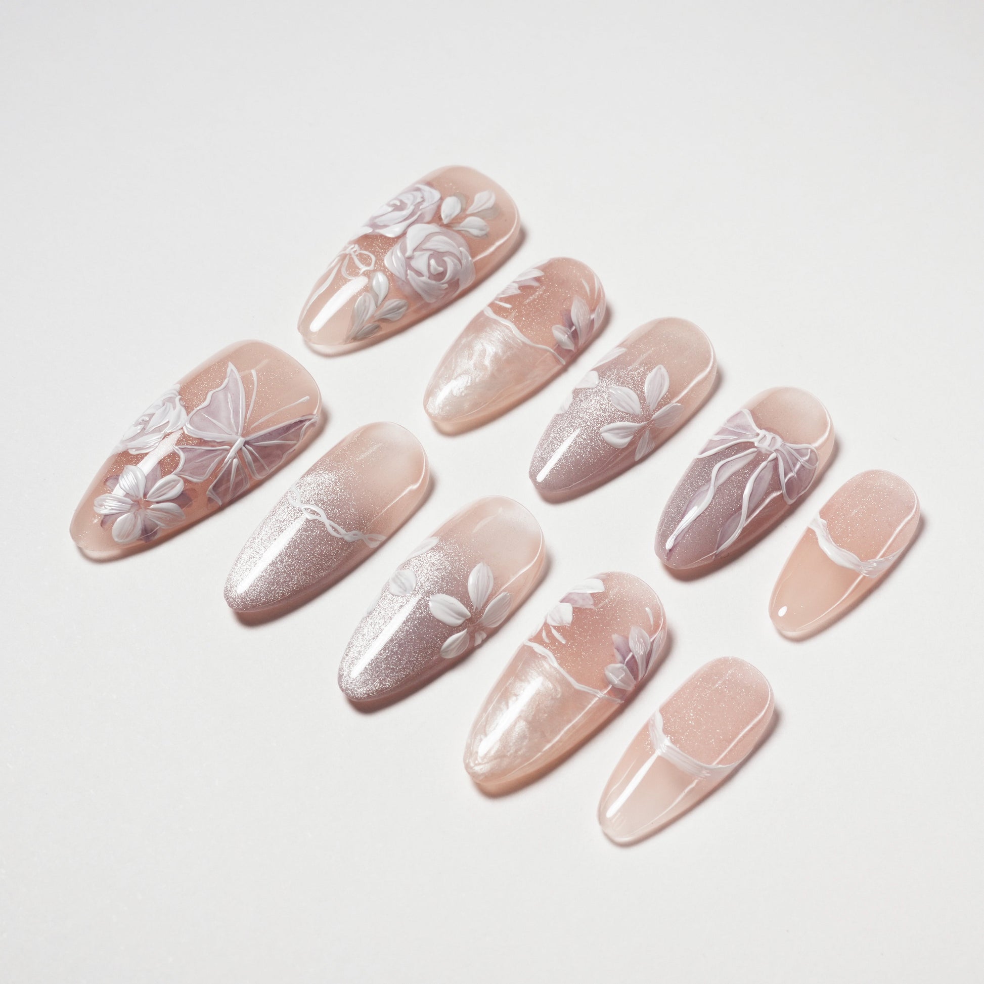 Set of nude pink false nails with delicate white floral and butterfly nail art designs