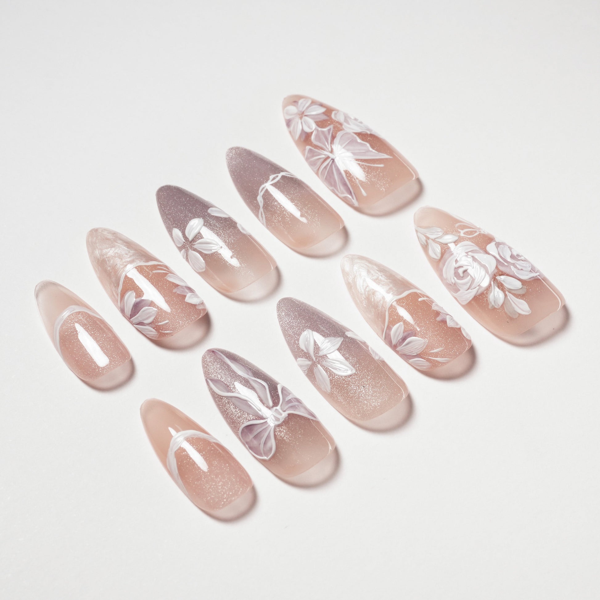 Set of long almond-shaped nude and mauve false nails with white floral and bow designs
