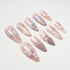 Set of nude and pink long press-on nails with white floral and leaf designs on white background