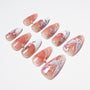 Handmade press-on nails with pink floral designs, white accents, pearls, and glossy finish