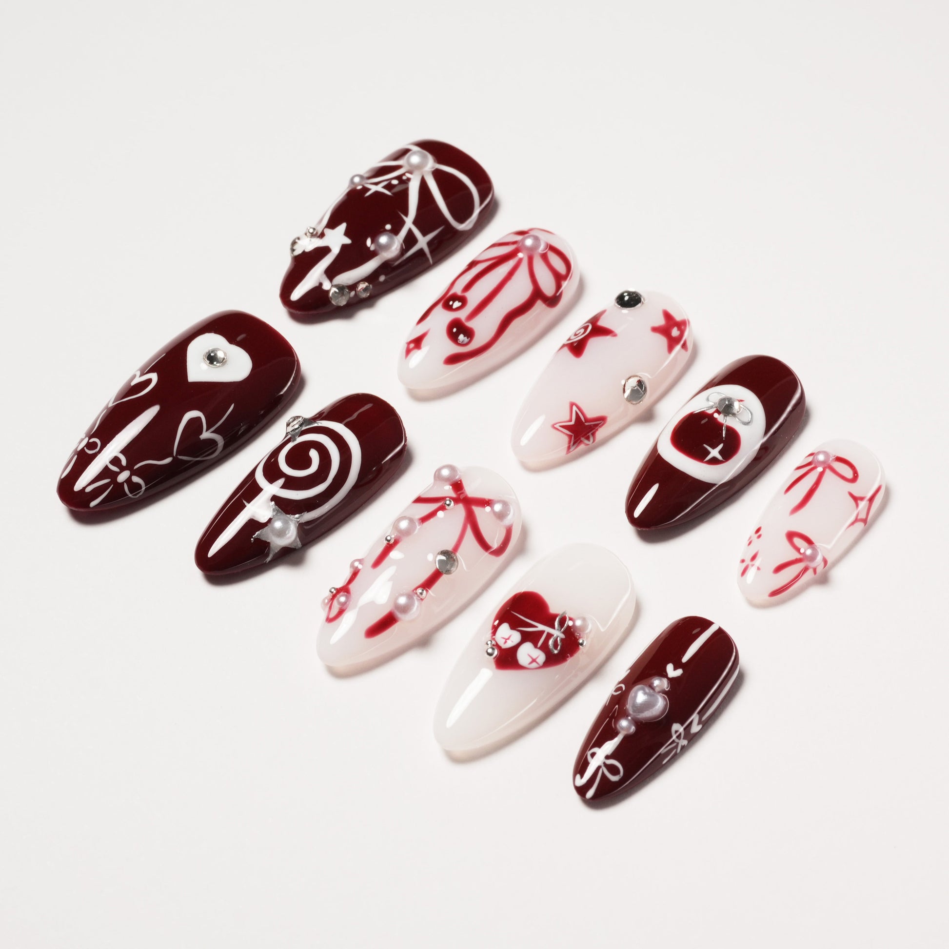 Set of red and white handmade press-on nails with heart, star, and bow designs, pearl accents