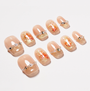 Nude and gold press-on nails with koi fish art, rhinestones, and pearl accents.