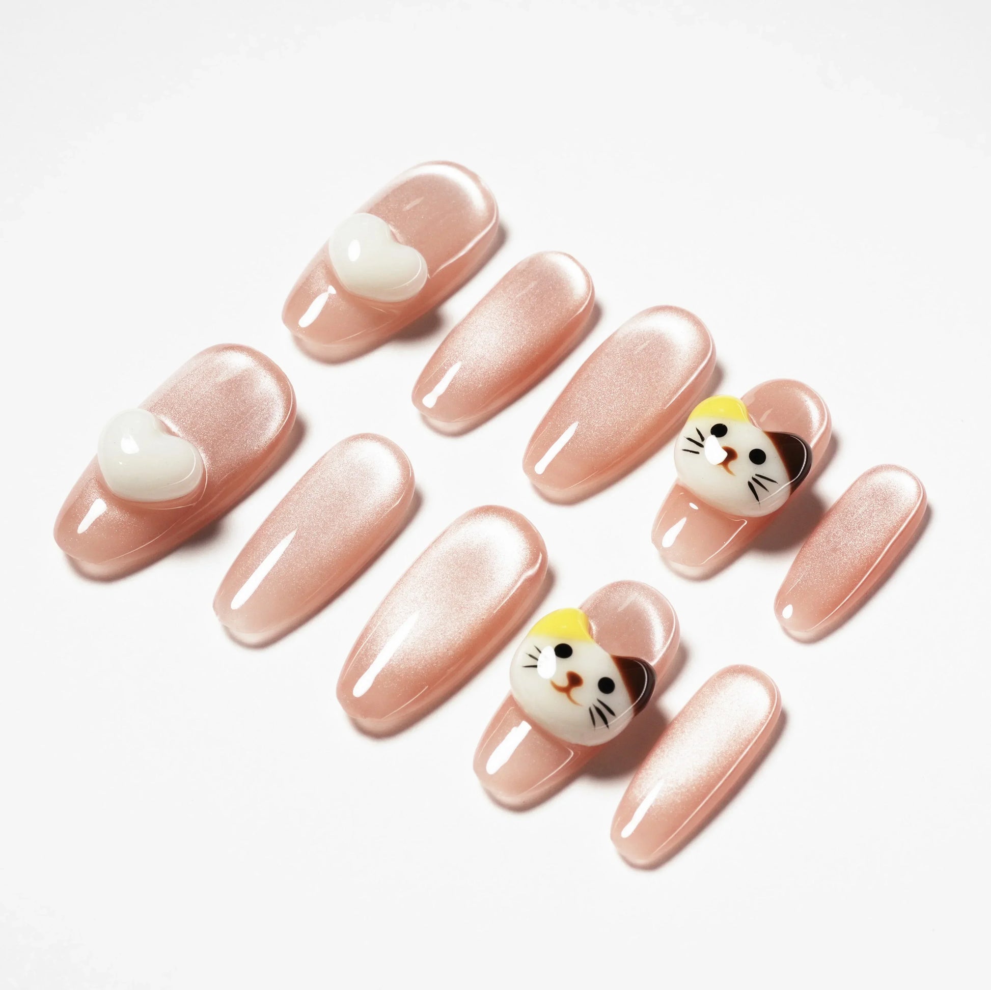 Set of glossy pink fake nails with white heart and 3D cat face accents on white background