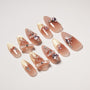 Nude pink stiletto false nails with gold glitter tips, 3D bows, and pink heart rhinestones