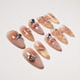 Set of nude pink and gold glitter nail art tips with 3D bows, heart gems, pearls, and rhinestones