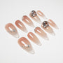 Glossy nude ombre press-on nails with silver accents and large crystal embellishments