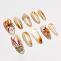 Handmade press-on nails with gold flakes and 3D floral designs on a neutral base