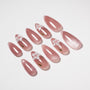 Glossy pink press-on nails with 3D white floral accents, arranged on a white background