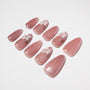 Glossy pink press-on nails with white 3D floral accents, arranged on a white background.