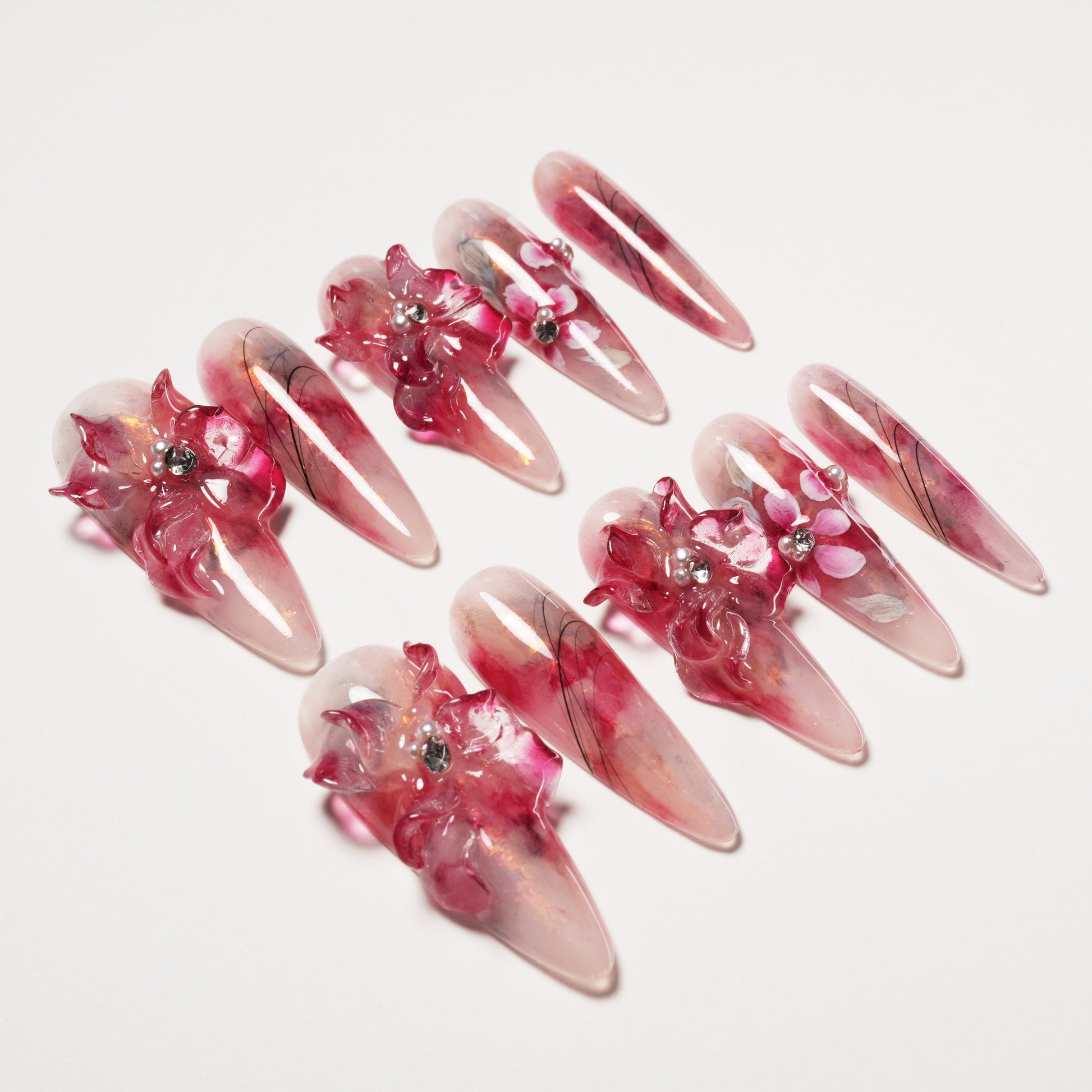 Set of long stiletto false nails with pink and red 3D floral designs and rhinestone accents