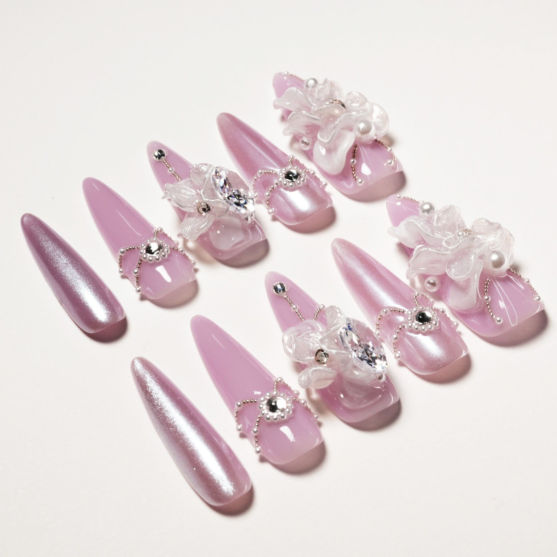 Elegant pink stiletto false nails with 3D floral accents and rhinestone decorations