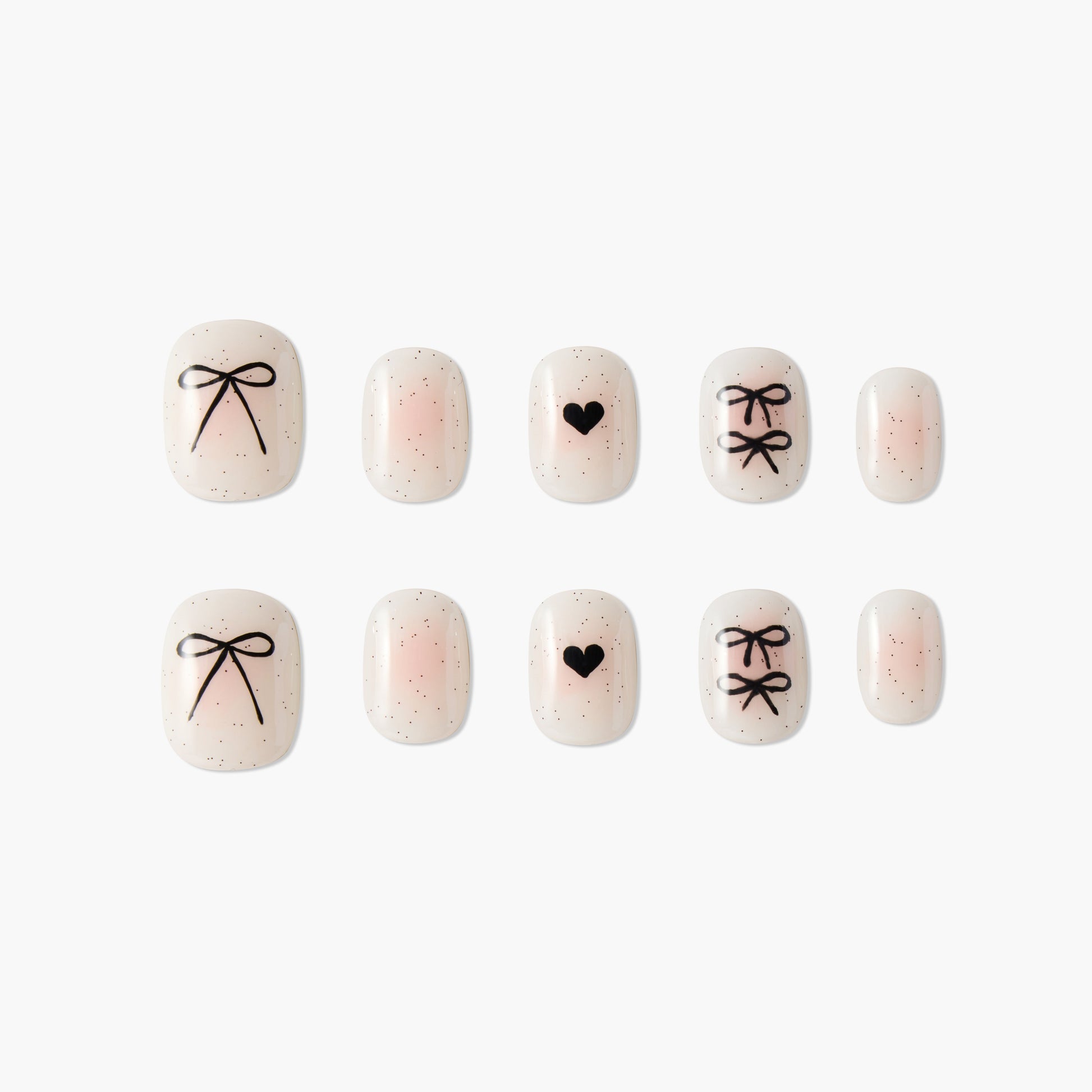 Pink nude press-on nails with black bow and heart designs, glitter accents, on white background.