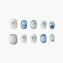 Set of blue and white marble-effect press-on nails with bow designs and rhinestone accents