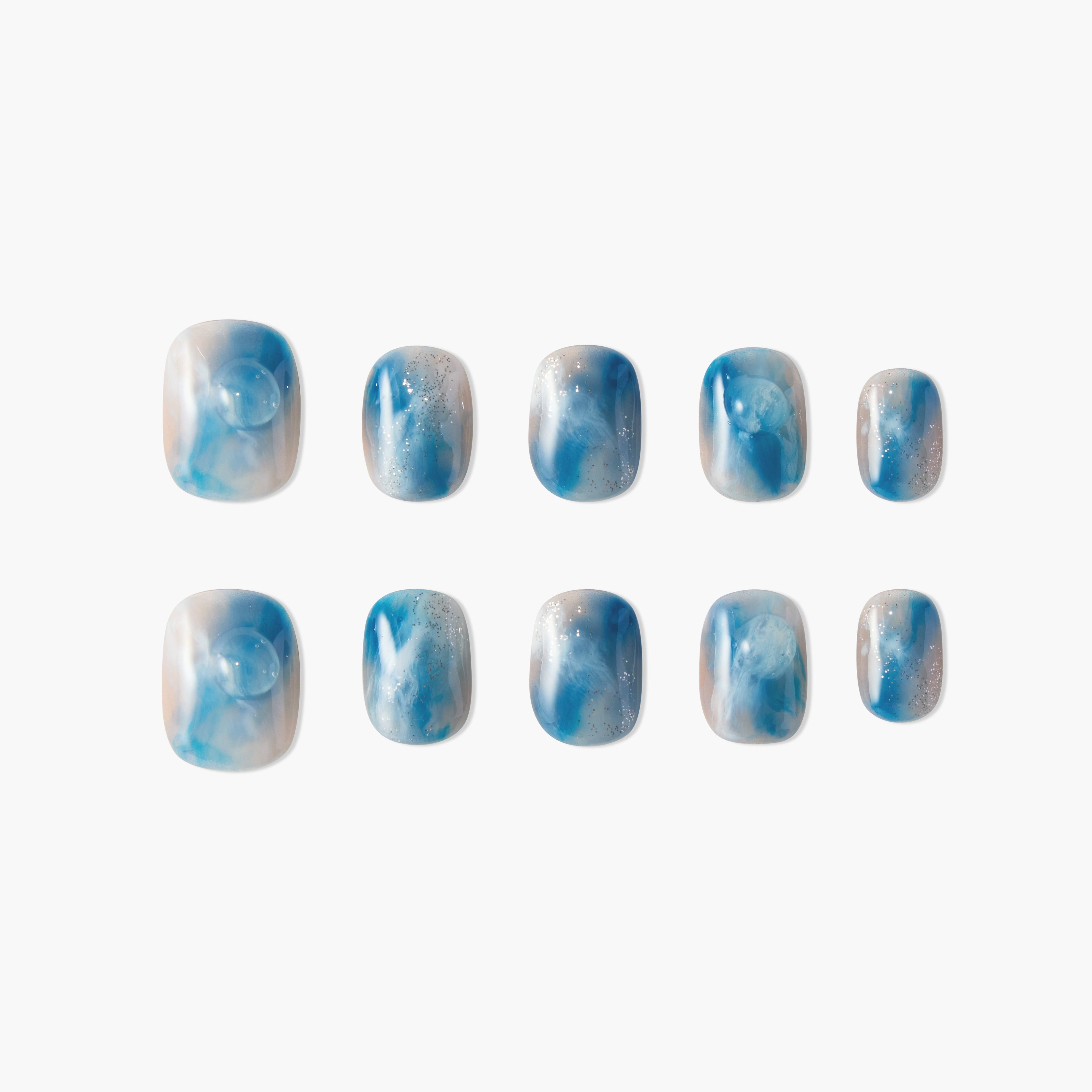 Set of blue and white marble effect false nails with silver glitter accents on white background