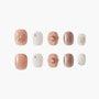 Handmade press-on nails in blush pink, white, and glitter, with floral and pearl accents.