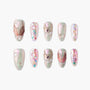 Handmade press-on nails with pearl, gemstone, and floral embellishments in iridescent pastel colors.