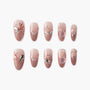 Set of pink glittery press-on nails with floral and star embellishments and rhinestones