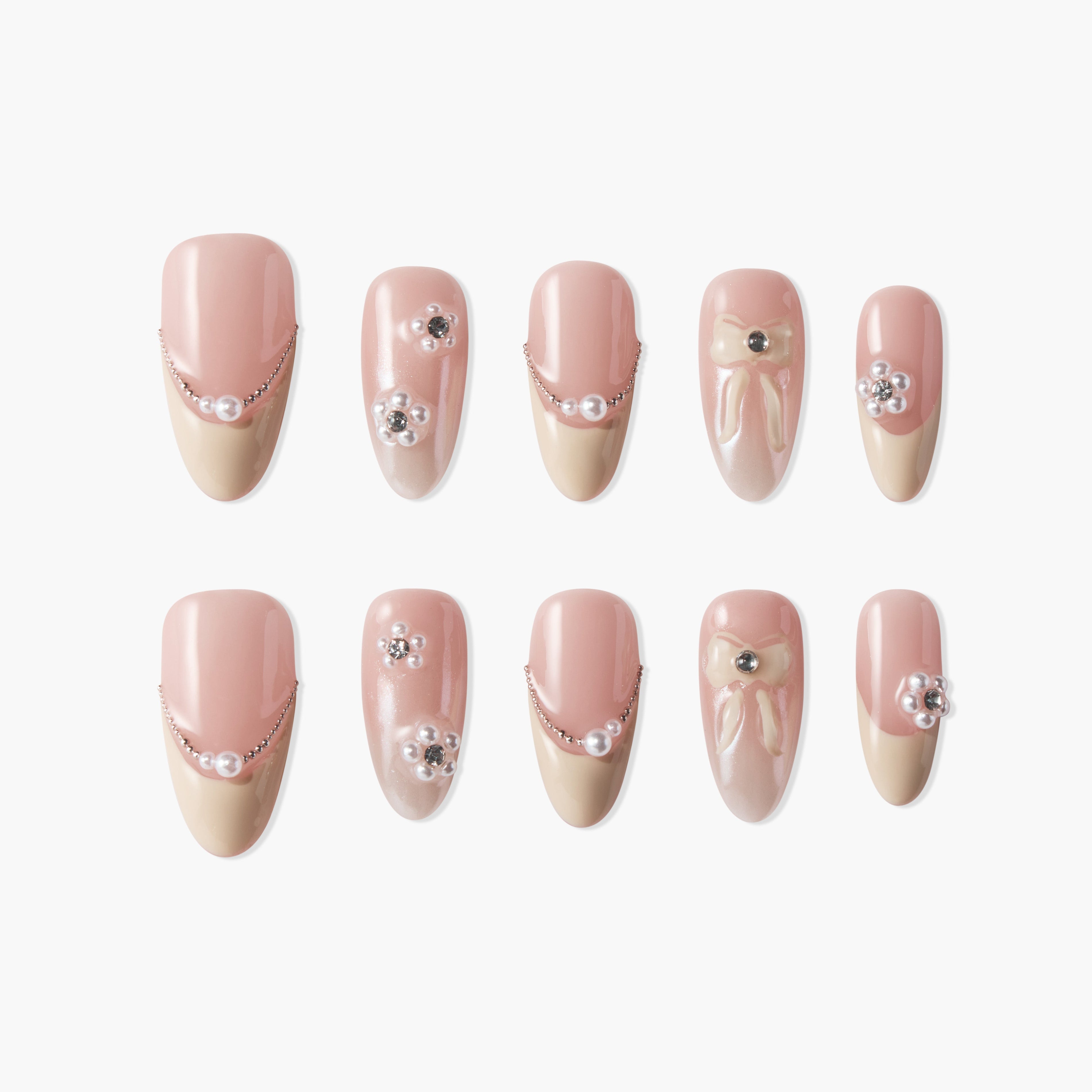 Set of pink and beige press-on nails with pearl, rhinestone, and bow nail art designs