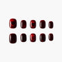 Glossy burgundy press-on nails with subtle heart designs, arranged on white background.