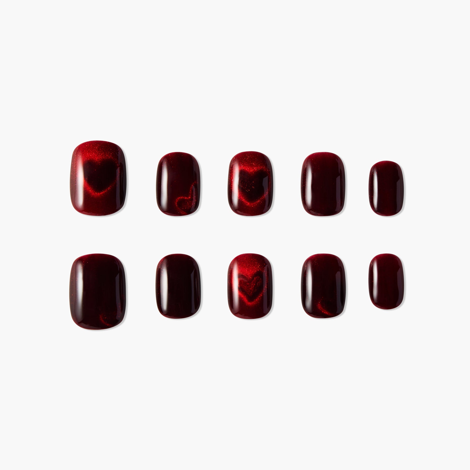 Glossy burgundy press-on nails with subtle heart designs, arranged on white background.