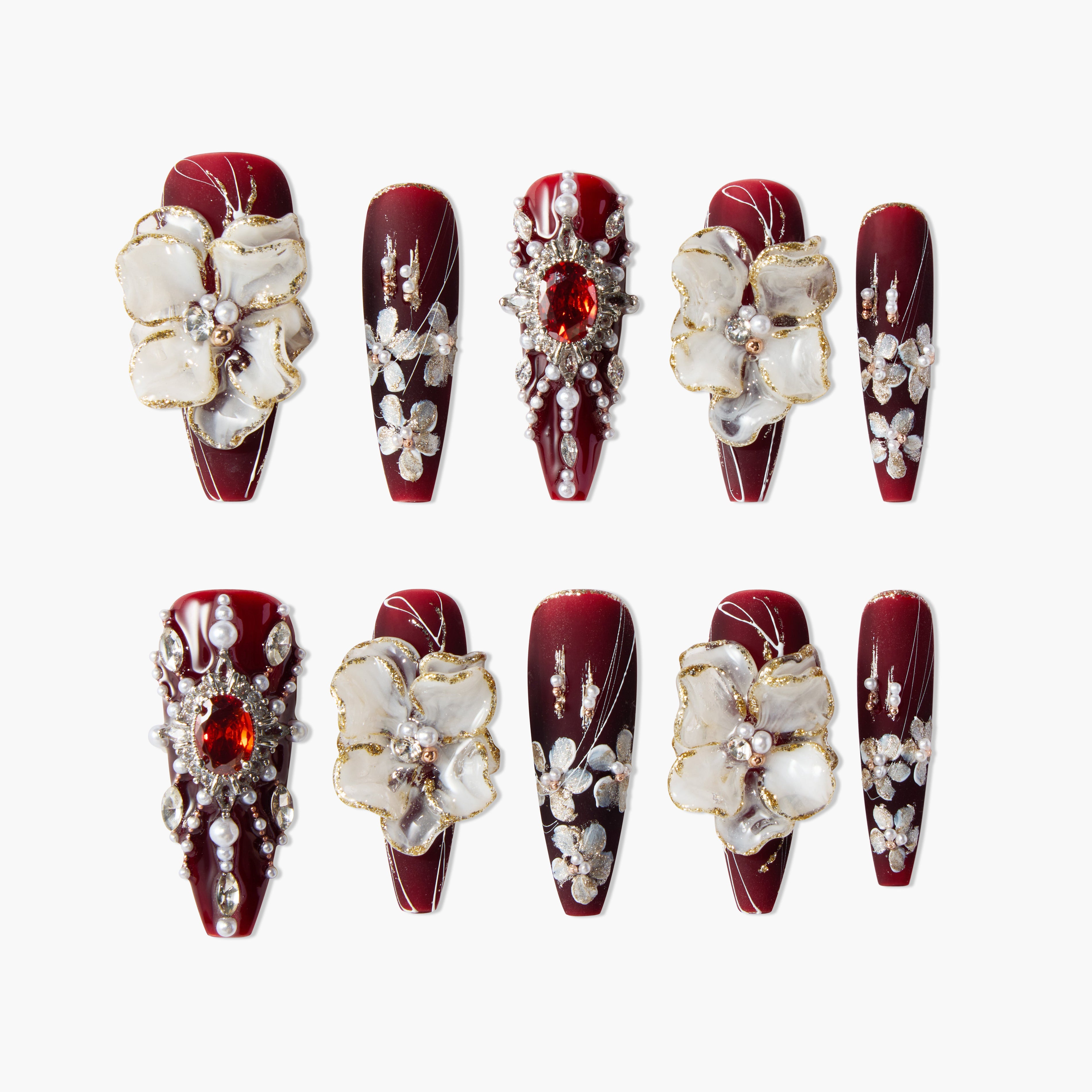 Set of red acrylic nails with white 3D flowers, gold accents, pearls, and rhinestone embellishments