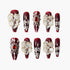 Set of red acrylic nails with white 3D flowers, gold accents, pearls, and rhinestone embellishments
