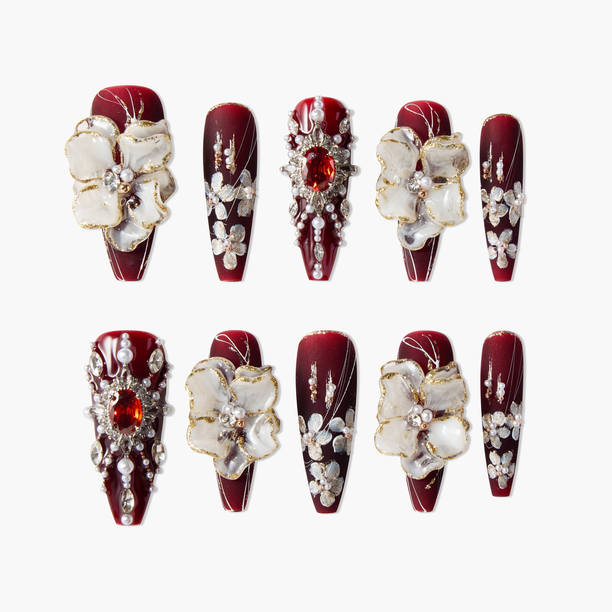 Set of red acrylic nails with white 3D flowers, gold accents, pearls, and rhinestone embellishments