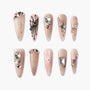 Set of nude long fake nails with glitter, black and white butterfly designs, and rhinestone embellishments