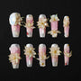 Handmade press-on nails with pink ombre, 3D flower accents, gold detailing, and pearl embellishments