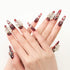 Hands with long red ombre nails decorated with white 3D flowers and rhinestones