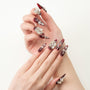 Long burgundy press-on nails with 3D floral and crystal embellishments on hands