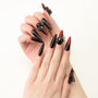 Long stiletto press-on nails in glossy black and red with 3D bow and jewel accents on hands