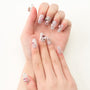 Hand with long glitter press-on nails featuring pink and silver gemstones, white background