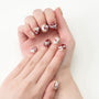 Hand with festive press-on nails featuring snowmen, snowflakes, and red accents.