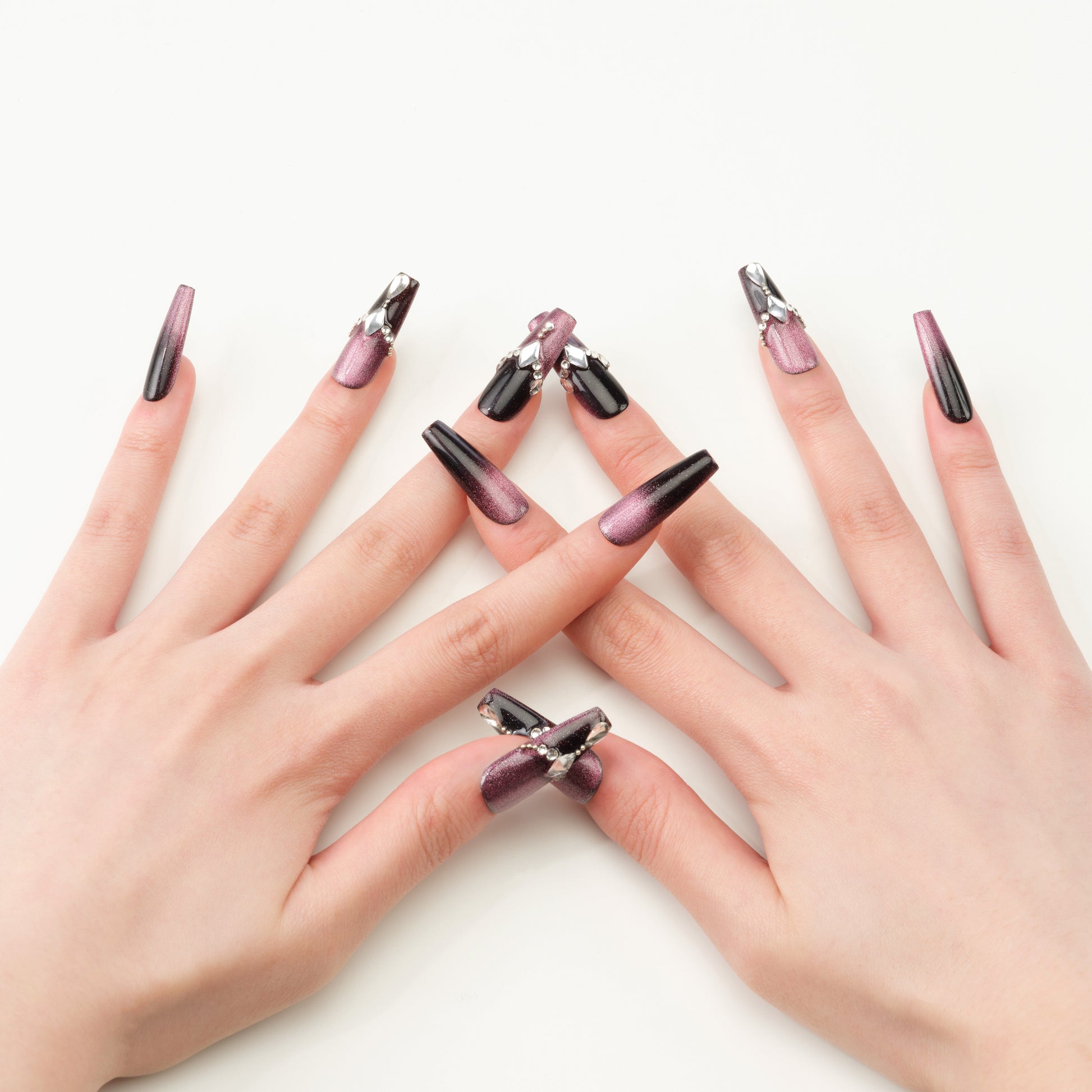 Coffin-shaped handmade press-on nails in metallic purple and black with crystal accents.