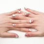 Handmade press-on nails with white and pink 3D bows, cartoon cats, and heart designs on a nude base.