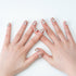 Hands with nude glossy nails adorned with silver rhinestones on white background