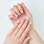Hand with French tip press-on nails featuring silver rhinestone accents on a white background.