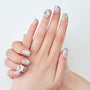 Hand with silver and clear handmade press-on nails featuring rhinestone and pearl accents